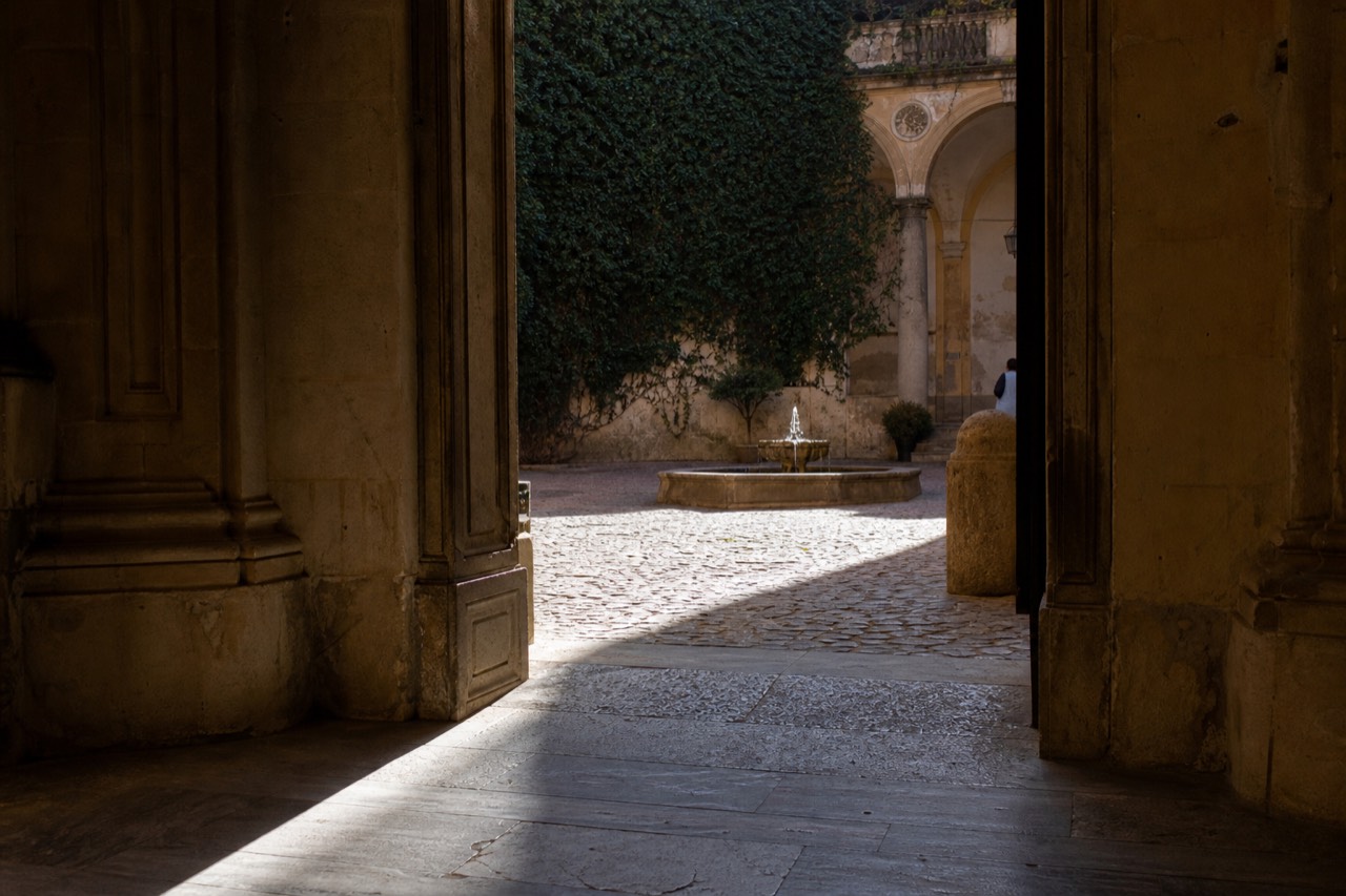 A quiet upper-floor corridor with tall windows overlooking a courtyard