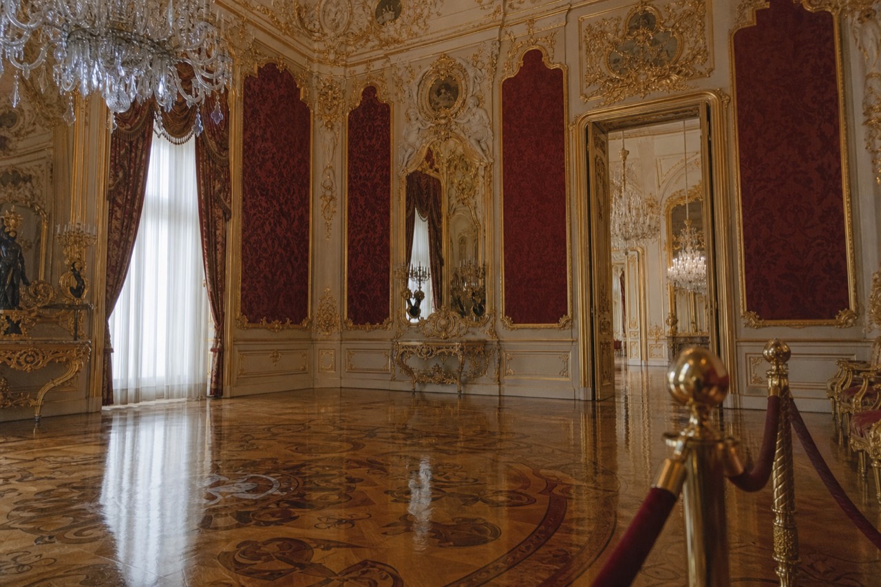 A mirrored ballroom with chandeliers, gilded frames and polished parquet in warm light