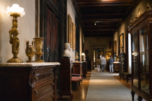 Panelled room in a historic Madrid mansion with framed oil paintings and a painted ceiling
