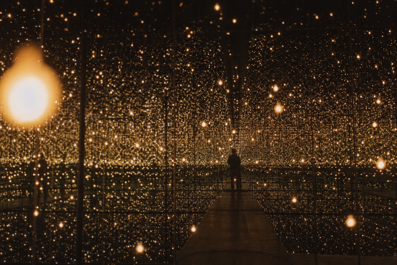 Mirrored infinity room repeating small lights into apparent darkness