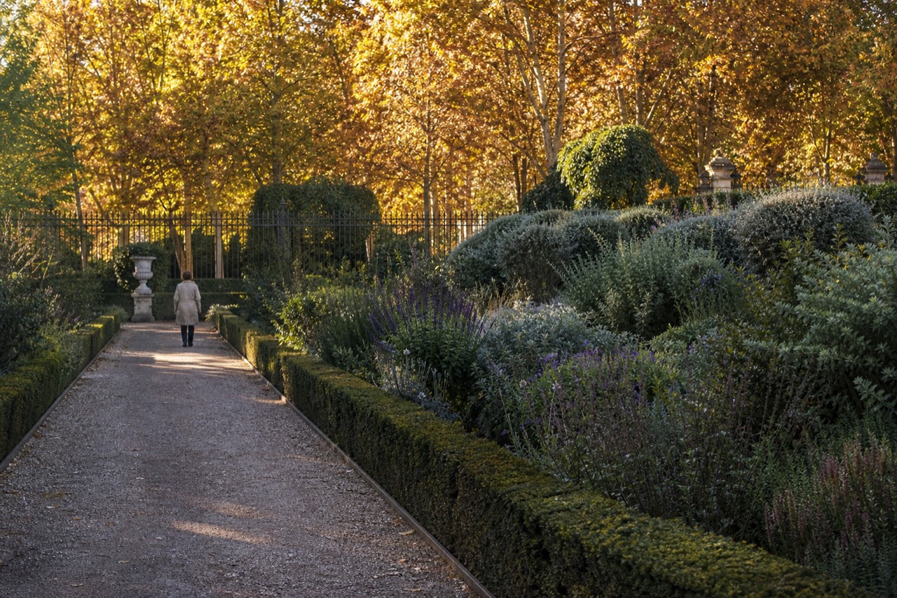 Formal palace gardens with clipped hedges and gravel paths below a long stone facade